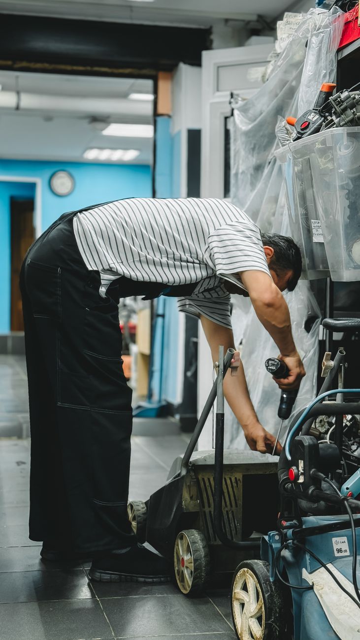 Technik opravuje benzínovou sekačku v dílně